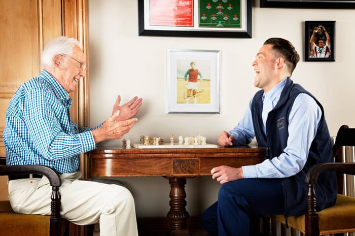 older man playing chess with carer