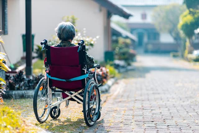 old lady in wheelchair in garden of sheltered accommodation